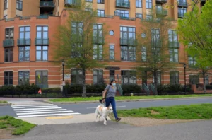 A woman walking wiht her dog and a building